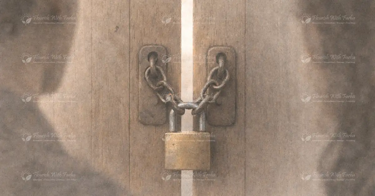 A wooden door secured with a metal chain and padlock, partially illuminated by soft light.