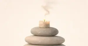 Stacked stones with burning candle representing the quiet exhaustion of functional burnout.